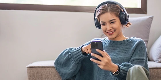  Frau hält Smartphone in der Hand und hört Musik.
